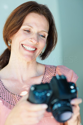 Happy middle aged woman holding a SLR camera