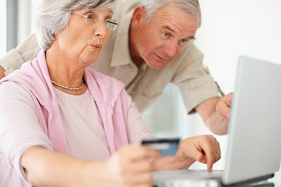 Shocked Older couple using a credit card to shop online