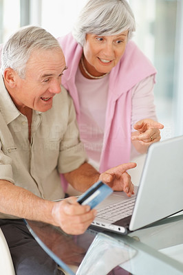 Elderly man and woman using a computer laptop for shopping