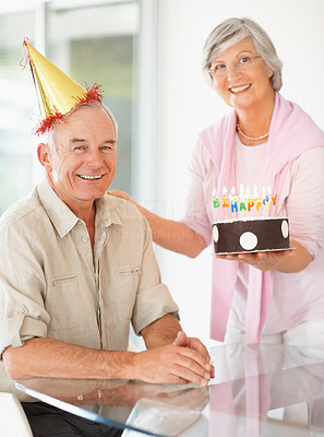 Senior woman celebrating husband's birthday with a cake
