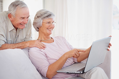 Portrait of smiling senior man watching his wife work on laptop