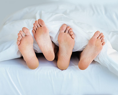 View of a couple\'s bare feet sleeping in bed