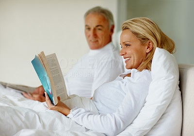 Woman in bed with husband reading a book