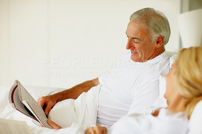 Man in bed with wife while reading a magazine