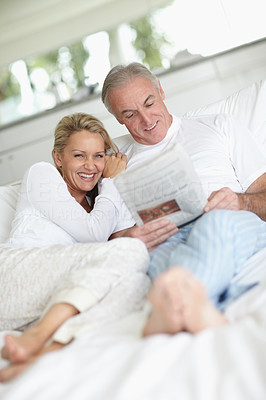 Couple in bed reading the newspaper together