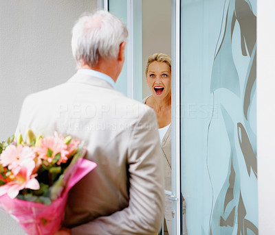 Man hiding a flower bouquet for a surprised woman