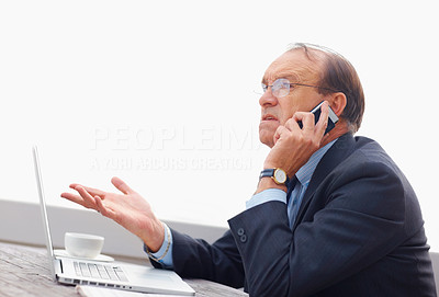 Unhappy senior business man with a laptop talking on the phone