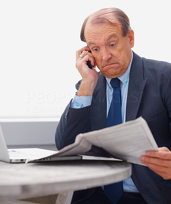 Surprised senior business man reading newspaper on the phone