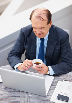 Smiling senior business man with laptop drinking coffee