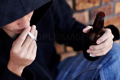 Topview of a person wearing a hoody, smoking and holding a bottle of beer