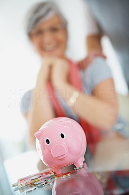 Blur image of woman with pink piggy bank in the foreground