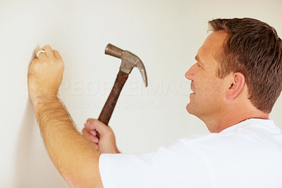 Man hitting a nail into a wall using a hammer