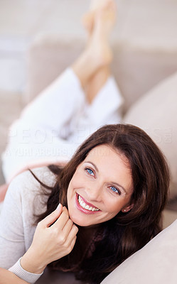 Happy thoughtful mature woman lying on couch