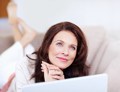 Day dreaming - Happy middle aged woman using laptop at home