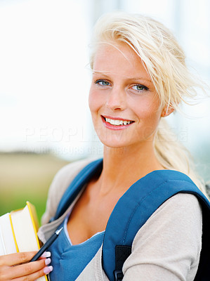 Pretty female student holding books , outdoors