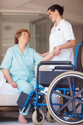 Nurse helping a senior woman onto a wheelchair