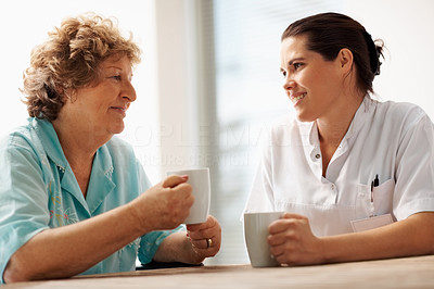 Elderly woman having a coffee with a young nurse
