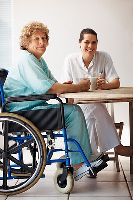 Senior patient on a wheelchair having coffee with a nurse