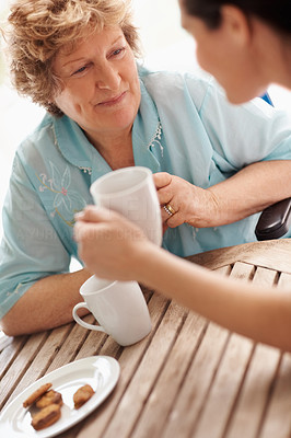 Happy senior patient having coffee with a nurse