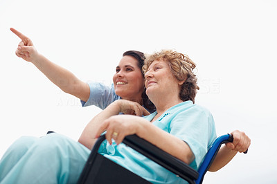Retired woman on a wheelchair , female pointing at something away