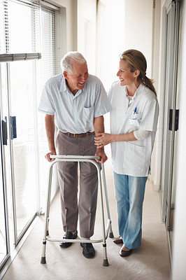 Doctor assisting an old man on a walker at the corridor