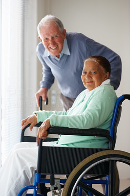 Elderly woman on a wheel chair , husband at the back