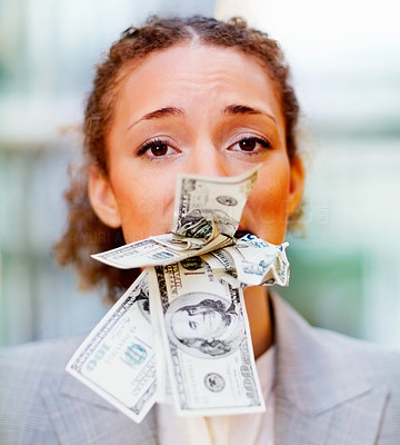 Unhappy young business woman with money in her mouth