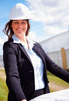 Happy business woman with blue prints at the construction site