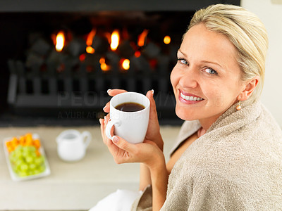 Happy woman having coffee by the fireplace