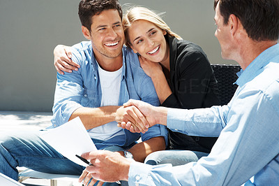 Happy young couple shaking hand with agent