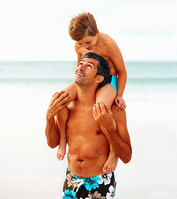 Man carrying his son on the shoulders while at the beach, looking at eachother