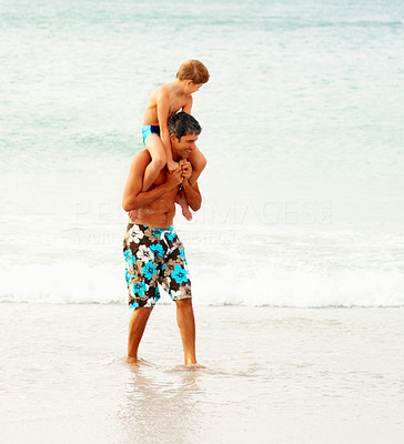 Father carrying his son on the shoulders wading on the beach