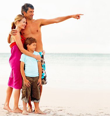 Happy family on their beach vacation, father pointing away