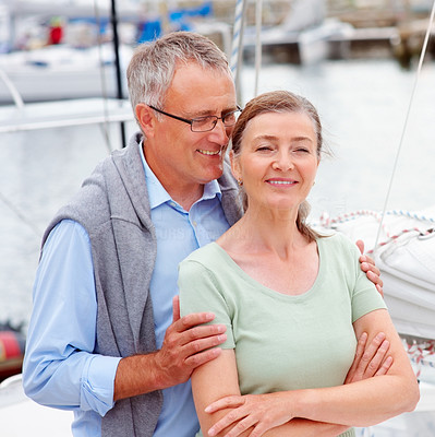 Handsome old man whispering a secret into wife\'s ears on a sailboat