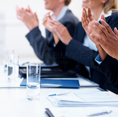 Business people clapping hands at a seminar, focus on glass on table