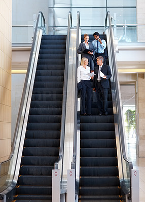Sophisticated business people on escalator, discussing business issues