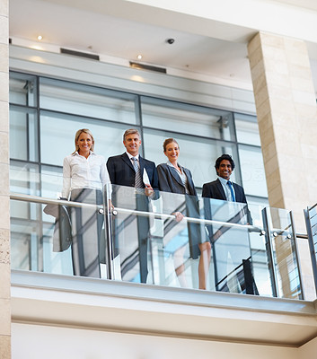 Successful business team standing by a glass railing