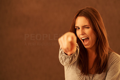 Pretty excited young woman pointing at you against brown background