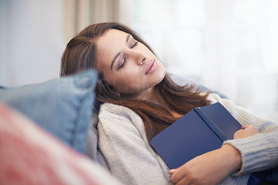 A young woman lying on the couch with a book