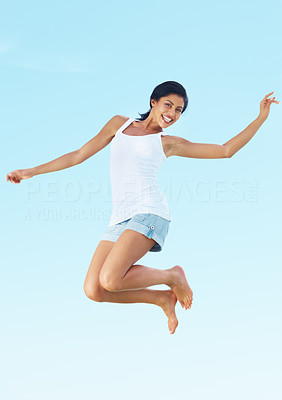 Excited young woman jumping against sky