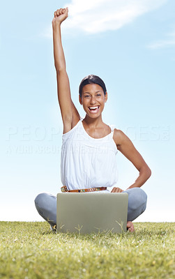 Cheerful woman on lawn with a laptop enjoying victory