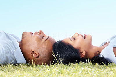 Happy couple lying head to head on a meadow