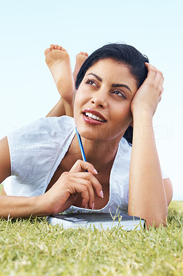Young female lying front on grass and thinking