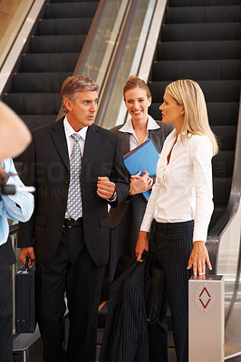 Sophisticated business people discussing issues in front of an escalator