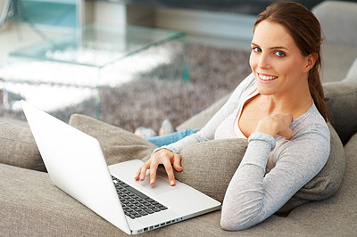 Sweet young lady on couch with laptop smiling