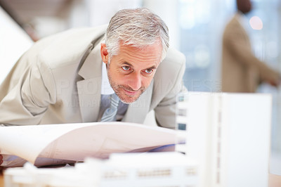 Mature business man looking closely at a building model