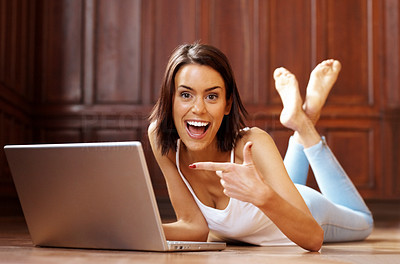 An excited young woman pointing at her new laptop
