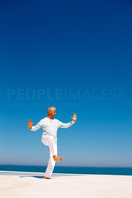 Senior man practicing martial arts on the beach