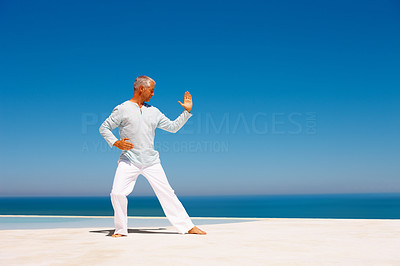 Fit old man practicing martial arts on the sea shore