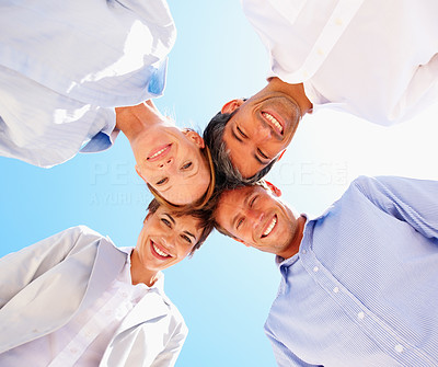 Professional group of business people with their heads together over blue sky